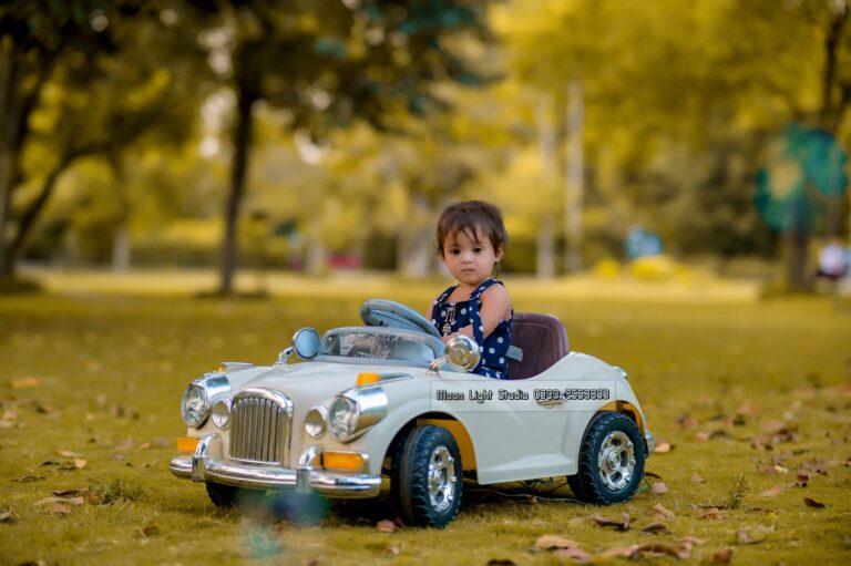 Baby enjoying outdoor photography session in an electronic car.
